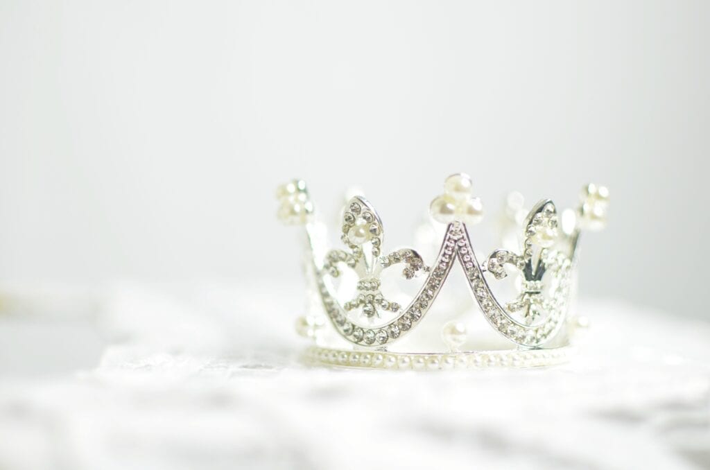 A delicate, sparkling silver crown on a soft white surface.