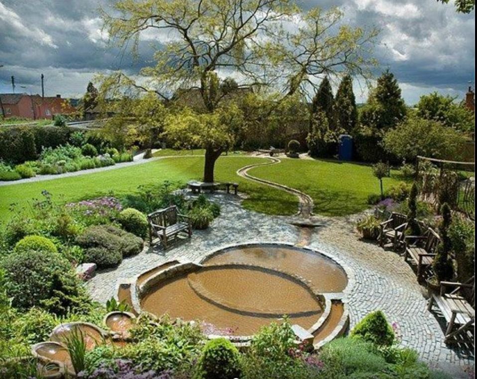 A serene outdoor hot tub surrounded by lush greenery and stone pathways.